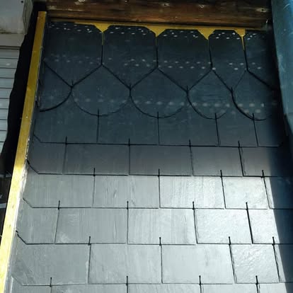 Détail de couverture en ardoise sur une petite toiture.