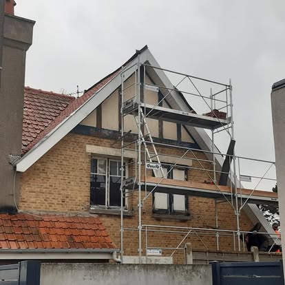 Façade de maison avec échafaudage pendant un chantier de toiture.