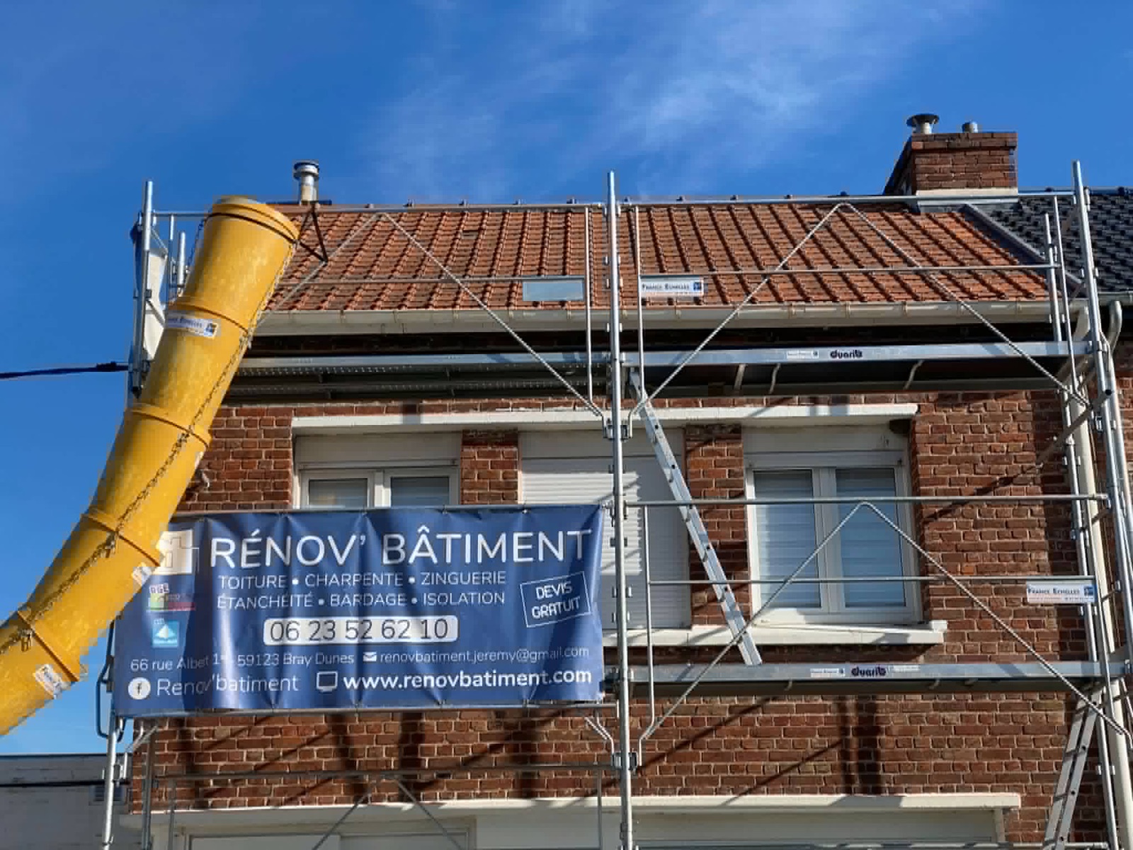 Maison en brique avec échafaudage pendant une intervention de couverture.