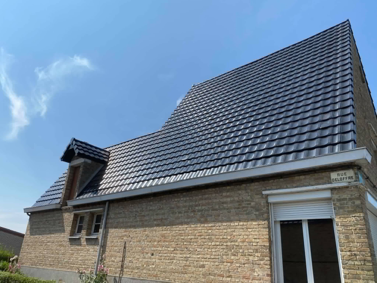 Toiture sombre neuve avec des tuiles brillantes et une fenêtre de toit.