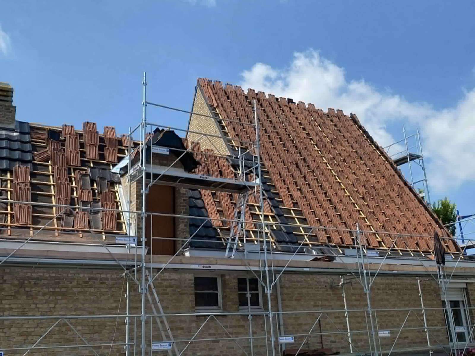 Pose de tuiles sur une toiture en cours de rénovation.