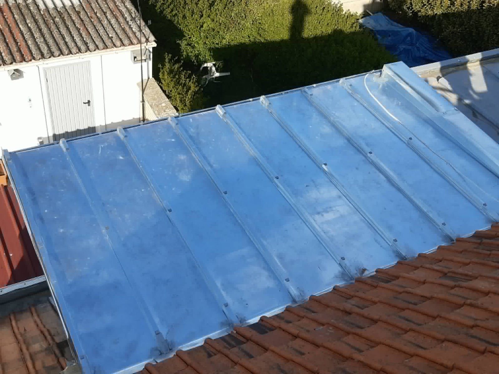 Couverture métallique bleue et raccords de zinguerie sur un bâtiment.