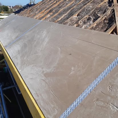 Panneaux posés sur une toiture pendant les travaux, avec l'ancienne couverture visible au-dessus.