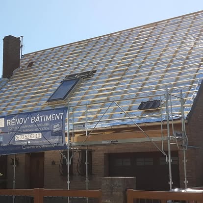 Toiture en cours de rénovation sur une maison en brique, avec échafaudage et fenêtre de toit.
