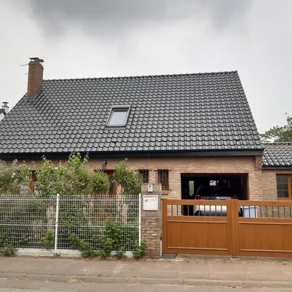 Maison en brique avec toiture sombre terminée et fenêtre de toit.